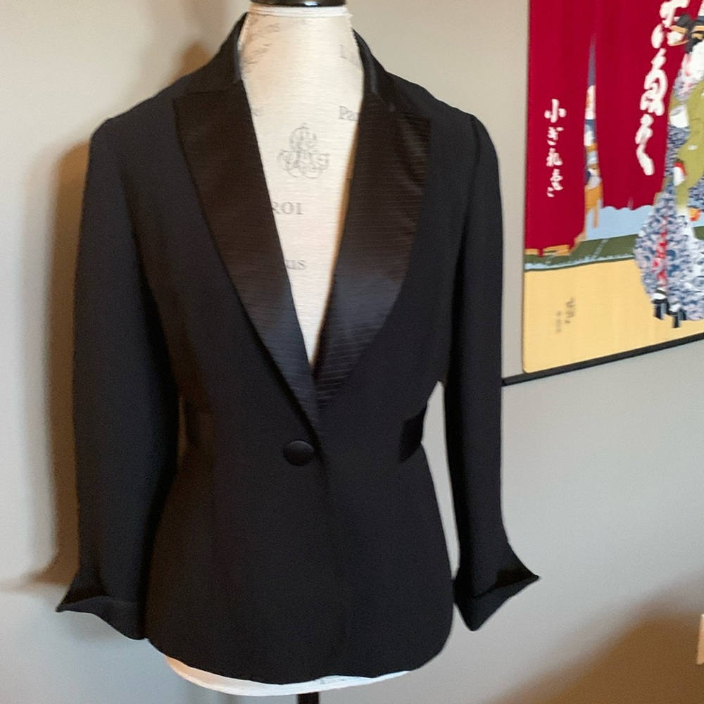 Black tuxedo look jacket. Lined. Has fine see through mesh back v design.